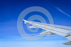 View over the clouds from the porthole of an airplane with plane wing