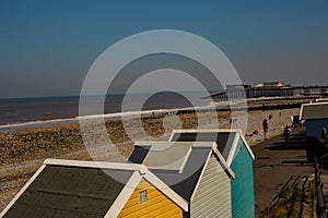 A view over Cromer beach and the beach huts and pier on a bright day