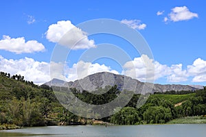 A view over a dam with white clouds and mountains near Franschhoek, South Africa