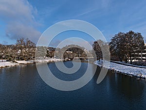 View over Danube River in winter with snow-covered riverbank and bare trees in the evening sun in Sigmaringen, Baden-WÃ¼rttemberg.