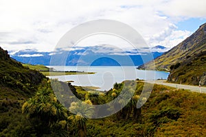 View over green grass and plants on lake with high rugged mountains background. Depp clouds hanging in mountain peak photo