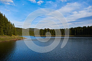 A view over the Lake Oasa in Mountains Sureanu with sky with clouds and forest