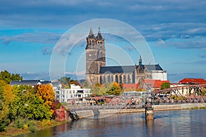 View over Magdeburg historical downtown, Elbe river, city park and the ancient medieval cathedral in golden Autumn colors at blue