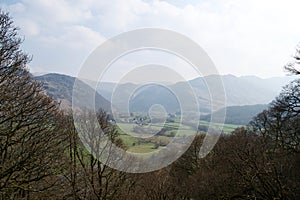 View over a pastoral valley; mountains, bare winter trees, green fields