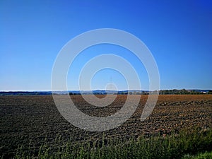 View over a plowed field on distant two masts of transmitters