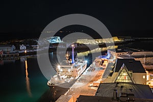 View over the port of Svolvaer on the Lofoten islands with cruise ship and wooden racks for drying cod fish at night