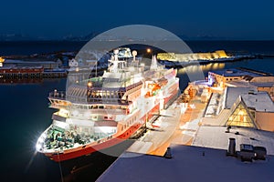 View over the port of Svolvaer on the Lofoten islands with cruise ship and wooden racks for drying cod fish at night