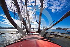View over river at calm winter day. Bow of red kayak in the Danube river.