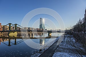 View over river Main in Frankfurt with Floesser Bridge and European Central Bank building with sun reflection in the photo