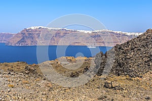 A view over the rugged landscape on the volcanic island of Nea Kameni, Santorini with Thira and the caldera in the background