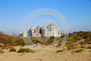 View over sand dunes with grass on coast town against clear blue summer sky - Knokke-Heist, Belgium photo