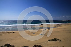 View over sand dunes with green ocean on Playa del Aljibe on white village on steep cliff El Cotillo - North Fuerteventura photo