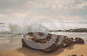 View over sandy beach of Atlantic Ocean with waves crashing on the rock and make the splashing water and white air foam