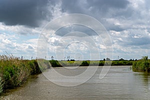 View over a sewer with dramatic clouds in the blue sky in Friesland, Lower Saxony