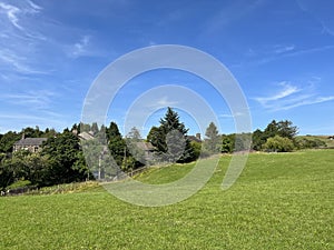 View over a sloping landscape, with stone houses and trees near, Slack lane, Delph, UK