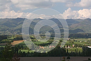 View over a small valley covered in sunlight with high mountains in the background