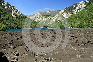 View over volcanic ashes on  secluded blue crater lake surrounded by mountains in  central Chile at Conguillio NP