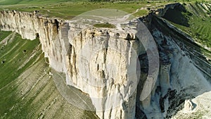 A view over white mountain cliffs, with hills and valleys, with green meadows on blue sky background. Shot. Aerial for