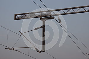 View of overhead electric lines used by train locomotives. Pole supporting the power lines used by electric train engines