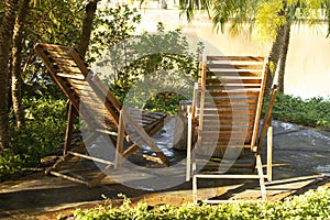 view of a pair of two modern striped brown wooden sun bed loungers near a lake in Brazil