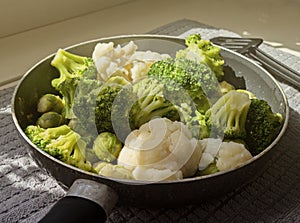 View of the pan with fresh defrosted vegetables and kitchen spatula