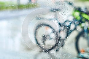 View of parked bicycles through the glass with drops of water