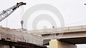 View of part of massive grey bridge with street light and construction crane