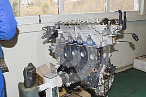 View of a partially disassembled automobile engine, with a new exhaust manifold gasket installed, mounted on an engine repair