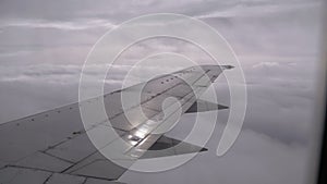 View from the Passenger Airplane Window on the Wing Flying above the Clouds