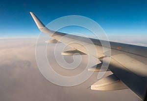 View from passenger window of wing of airplane flying in sky on sunny day. Concept of travel