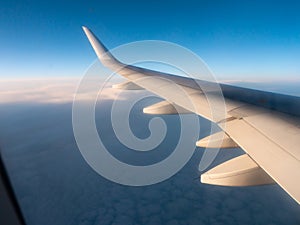 View from passenger window of wing of airplane flying in sky on sunny day. Concept of travel