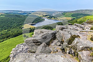 A view past boulders on the cliff edge of  Bamford Edge towards Ladybower reservoir, UK