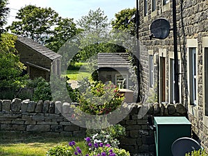 View past, old stone cottages, and gardens on, Coplowe Lane, Wilsden, UK