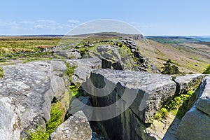 A view past slabs of millstone on the highest point on the top of the Stanage Edge escarpment in the Peak District, UK