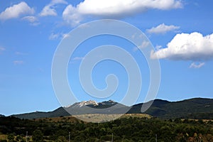 View of the peaks of the chain of mountains of the Maiella group, Pietra Cernaia area, under a blue sky with large white clouds, A