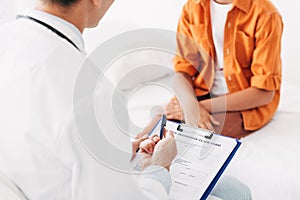 View of pediatrist writing in clipboard while examining child in clinic