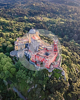 View of Pena Palace, a colorful Romanticist castle building on hilltop during a beautiful sunset, Sintra, Lisbon, Portugal.