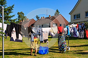 View of people hanging laundry on clothesline in backyard with houses and clear blue sky background