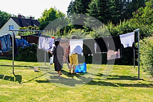 View of people hanging laundry on clothesline in backyard with houses and trees in background