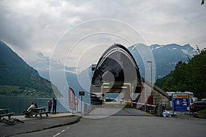 View of people sitting by Fjord sea near the port of the tourist ferry in Geiranger village, Norway