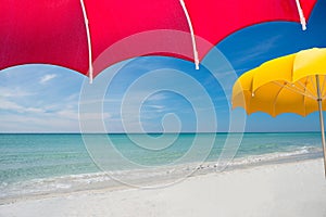 View of perfect pristine beach from under bright red umbrella