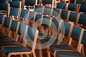 View of perfectly aligned empty wooden chairs on a conference hall