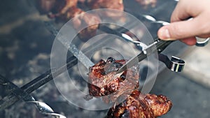 View person cutting chicken or turkey meat fillet with knife checking readiness at brazier cooking on burning coal with