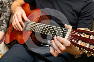 View of a person hand on a wooden handle near the strings of a guitar