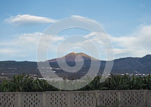 View of pico del Teide volcano mountain with sunset red colored peak seen from Alcala village with concrete wall surrounding