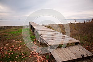 View of a pier on a lake with shore covered by autumn leaves