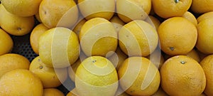 View of pile of oranges being sold in market place, top view of sunkist oranges, yellow round fruits, fresh fruit background