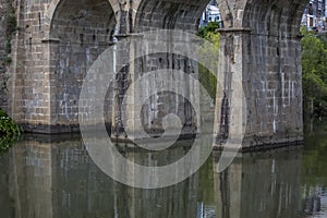 View at the pillars of the old roman bridge over river, in stone, with vegetation around photo