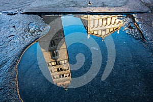 View of Pistoia Cathedral (Cattedrale di San Zeno) bell tower reflected in a puddle, Tuscany, Italy