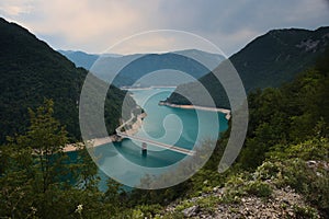 A view into the Piva lake going through a valley with an old rusty bridge connecting both shores